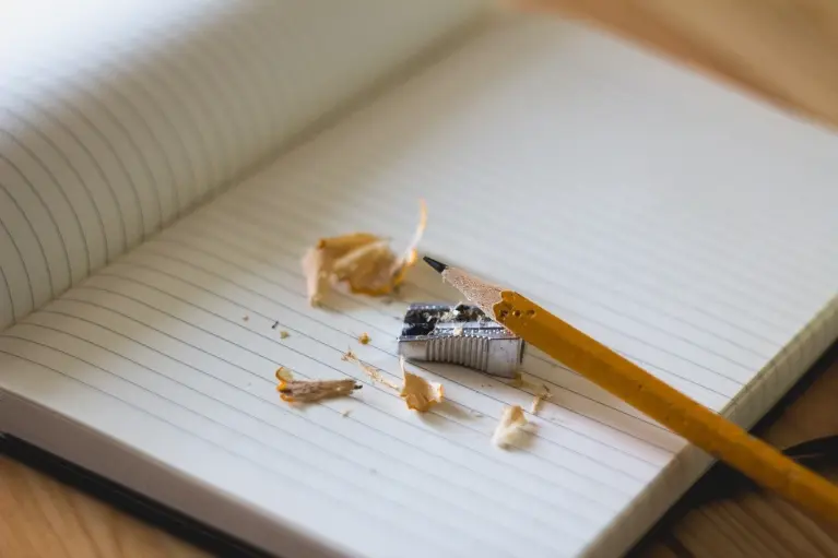 illustration montrant un cahier de note ouvert en deux avec un crayon de papier et un taille crayon